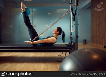 Sporty woman in sportswear doing stretching pilates exercise in gym. Fitness workuot in sport club. Athletic female person, aerobics. Sporty woman doing pilates exercise in gym