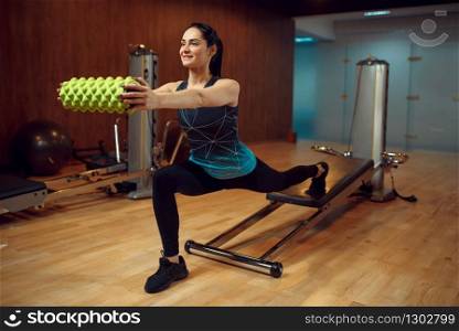 Sporty woman in sportswear, pilates training with roll on exercise machine in gym. Fitness workuot in sport club. Athletic female person, aerobics indoor, body stretching. Sporty woman, pilates training with roll