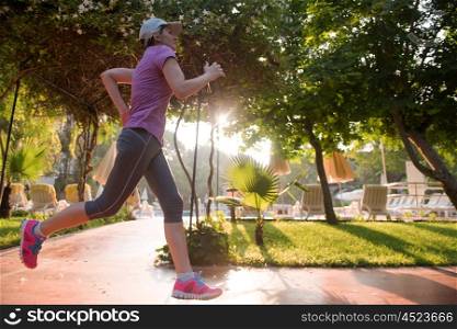 sporty woman jogging on sidewalk at early morning
