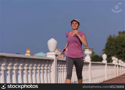sporty woman jogging on sidewalk at early morning