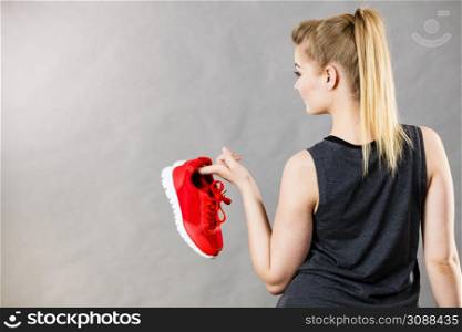 Sporty woman presenting sportswear trainers red shoes, comfortable footwear perfect for workout and training.. Woman presenting sportswear trainers shoes