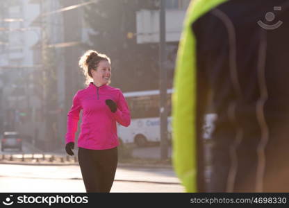 sporty woman running on sidewalk at early morning jogging with city sunrise scene in background