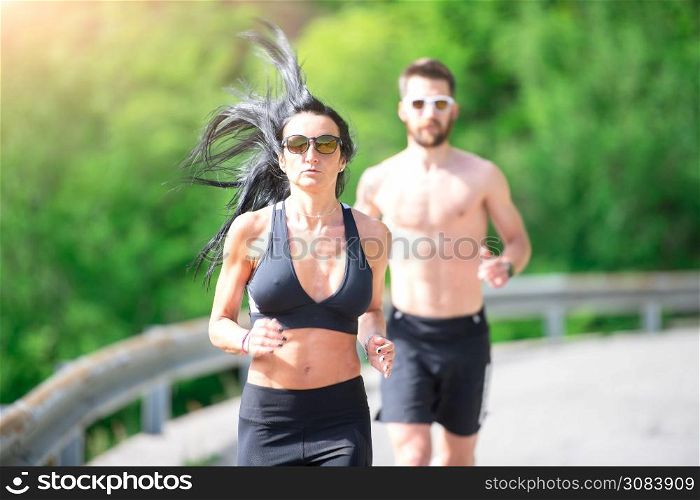 Sporty woman runs in front of her athletic trainer