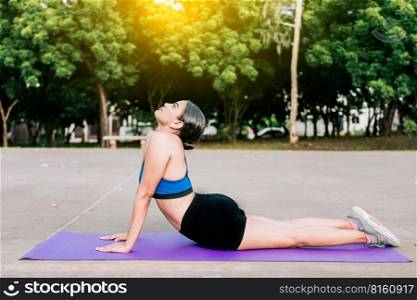 Sporty woman stretching her body doing cobra pose in a park. Athlete woman doing cobra pose in a park. Athlete woman doing yoga Bhujangasana in a park