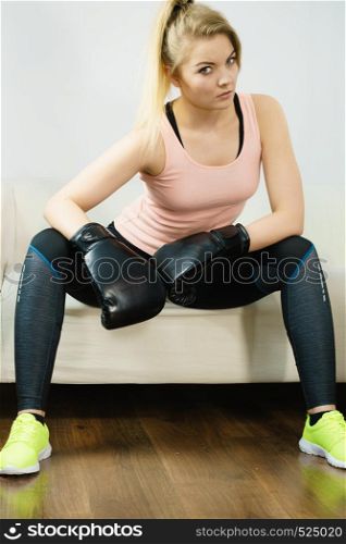 Sporty woman wearing black boxing gloves, fighting. Studio shot on grey background.. Woman wearing boxing gloves