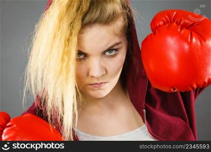 Sporty woman wearing red boxing gloves, fighting. Studio shot on dark background.. Woman wearing boxing gloves