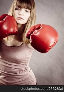 Sporty woman wearing red boxing gloves, fighting. Studio shot on grey, background.. Woman wearing boxing gloves