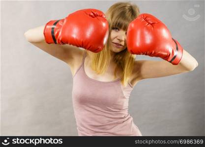 Sporty woman wearing red boxing gloves, fighting. Studio shot on grey, background.. Woman wearing boxing gloves