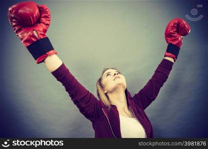 Sporty woman wearing red boxing gloves, winning fight, being motivated feeling relief and happiness. Studio shot on dark background.. Woman winner wearing boxing gloves