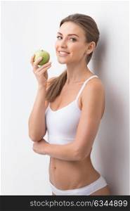 Sporty woman with apple. Young attractive sporty woman in white underwear holding green apple