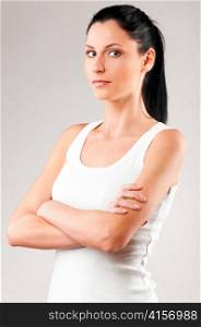 sporty woman with folded hands on grey background