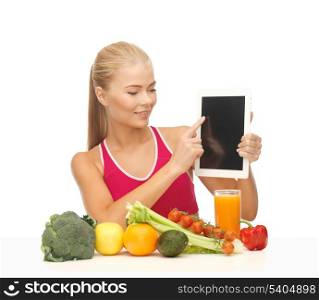 sporty woman with fruits and vegetables pointing at tablet pc