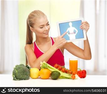sporty woman with fruits and vegetables pointing at tablet pc