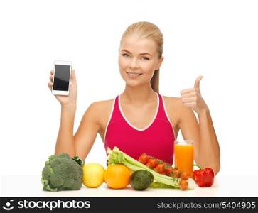 sporty woman with fruits and vegetables showing smartphone