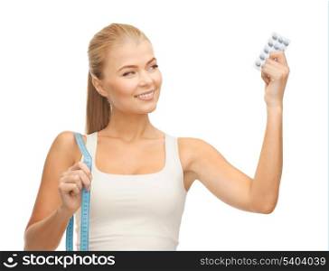 sporty woman with measuring tape and diet pills