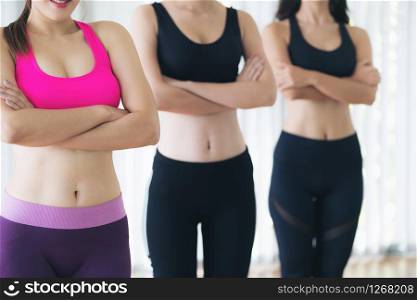 Sporty women team standing in fitness gym, cross arms with confidence. Healthy lifestyle and wellness concept.