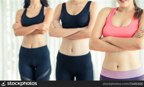 Sporty women team standing in fitness gym, cross arms with confidence. Healthy lifestyle and wellness concept.