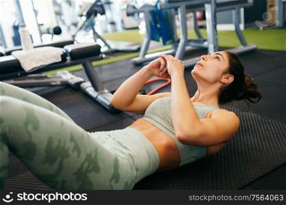 Sporty young female, wearing sportswear, on yoga mat doing situps in gym. Fitness woman doing abs crunches.. Young sportswoman on yoga mat doing situps in gym.