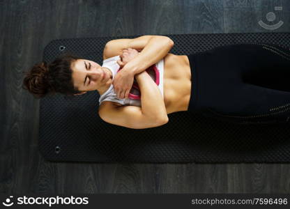 Sporty young female, wearing sportswear, on yoga mat doing situps with plate weights in gym. Fitness woman doing abs crunches.. Young sportswoman on yoga mat doing situps in gym.