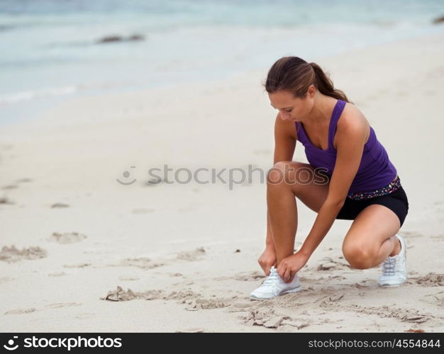 Sporty young woman doing her laces on the sea coast