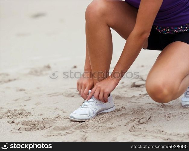 Sporty young woman doing her laces on the sea coast