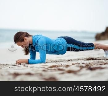 Sporty young woman exercising on the sea coast