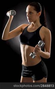 Sporty young woman holding dumbbells on black background
