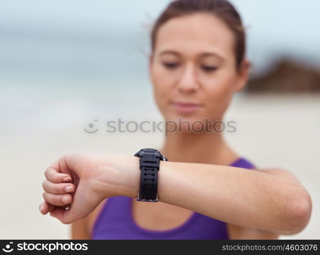 Sporty young woman looking at her wristwatch