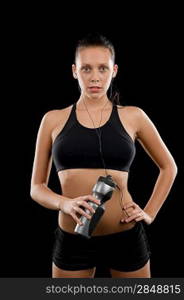 Sporty young woman posing with headphones and bottle black background