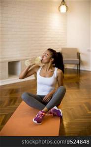 Sporty young woman resting and having break after doing exercise at home