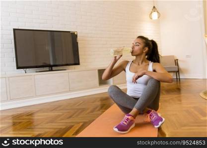 Sporty young woman resting and having break after doing exercise at home