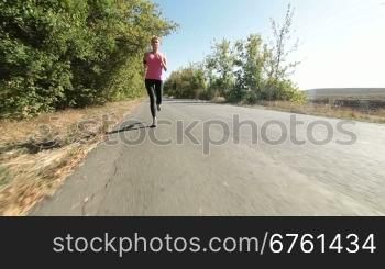 Sporty young woman runner jogging on the road wide angle