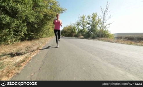 Sporty young woman runner jogging on the road wide angle