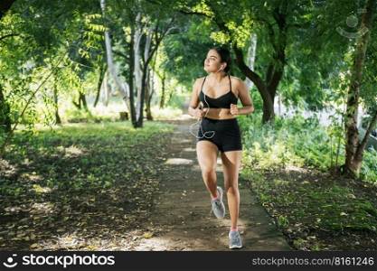 Sporty young woman running in a park. A girl running in a park while listening to music. Lifestyle of beautiful girl running in a park surrounded by trees. Healthy lifestyle concept. Sporty young woman running in a park. A girl running in a park while listening to music. Lifestyle of beautiful girl running in a park surrounded by trees. Healthy lifestyle concept.