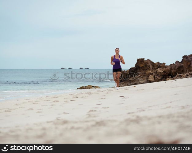 Sporty young woman running on the sea coast