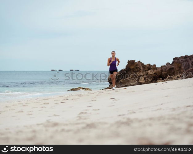 Sporty young woman running on the sea coast