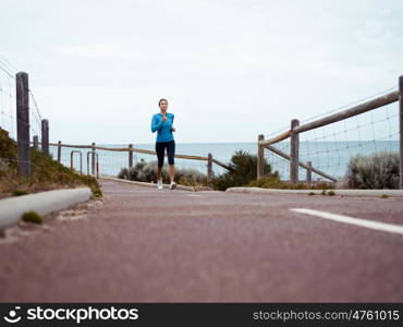 Sporty young woman running on the sea coast