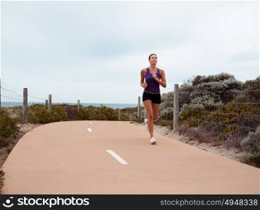 Sporty young woman running on the sea coast