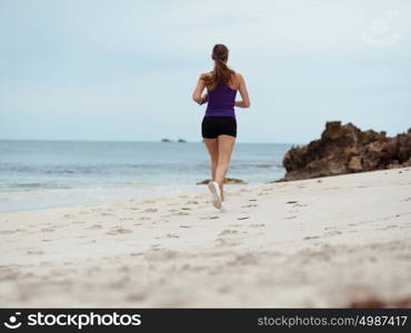 Sporty young woman running on the sea coast