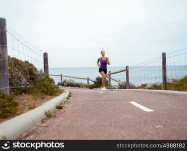 Sporty young woman running on the sea coast