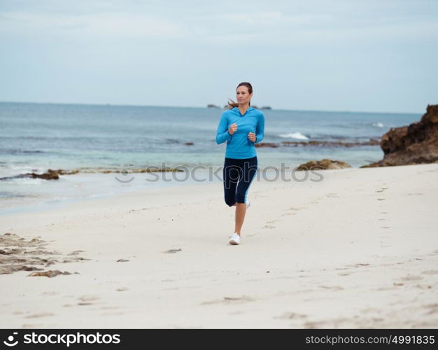 Sporty young woman running on the sea coast