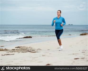 Sporty young woman running on the sea coast