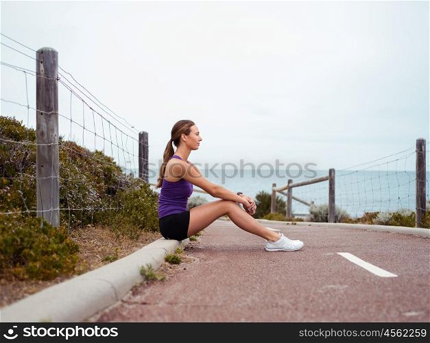 Sporty young woman sitting on the path