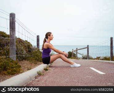 Sporty young woman sitting on the path