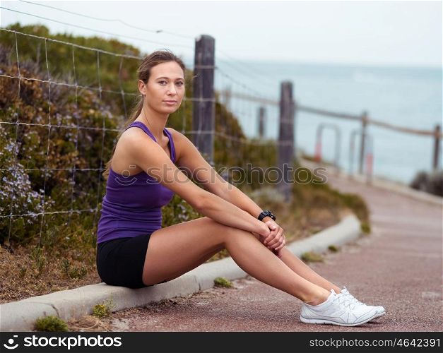 Sporty young woman sitting on the path