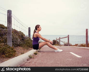 Sporty young woman sitting on the path