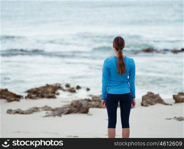 Sporty young woman standing in front of the ocean