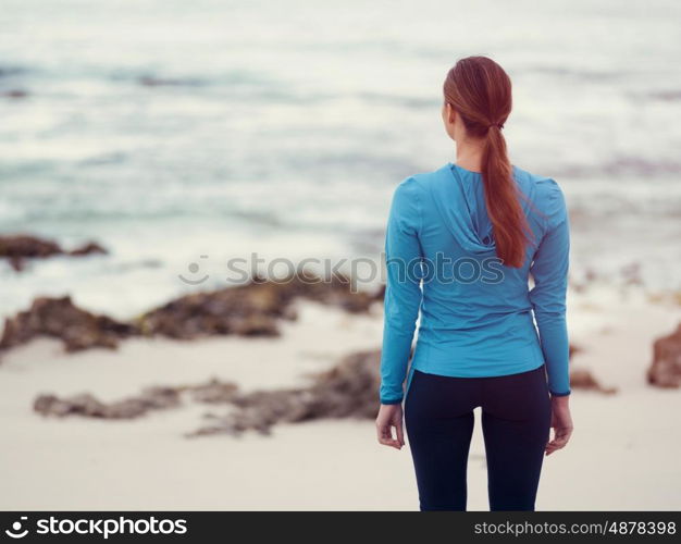 Sporty young woman standing in front of the ocean