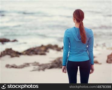 Sporty young woman standing in front of the ocean