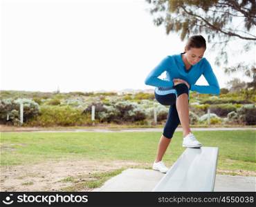 Sporty young woman stretching in the park